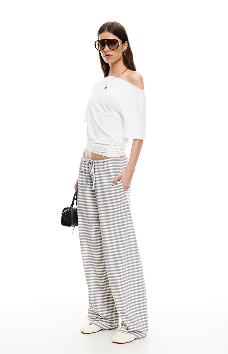 Side view of ash grey and white striped wide-leg pants with a drawstring waist and side pockets
