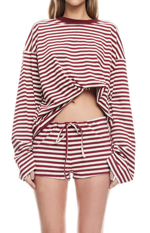 model wearing wine red and white striped lounge shorts with an adjustable drawstring paired with a matching long sleeved top