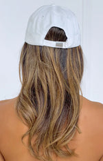Rear view of a cream baseball cap showing the adjustable strap and silver buckle