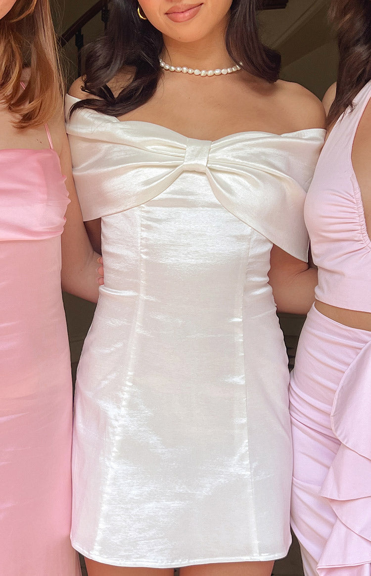 Close-up of the white shimmery off-shoulder mini dress with a large bow detail on the bust