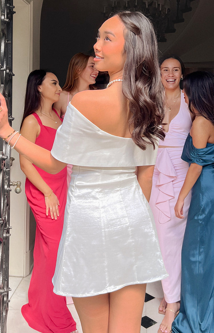 Back view of a white off-shoulder mini dress with a wide flounce neckline and shimmery A-line skirt