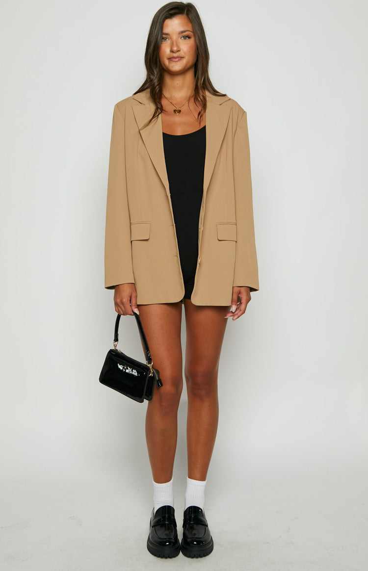 Full front view of a tan oversized blazer worn open with notched lapels and flap pockets