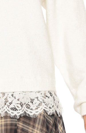 Close-up of the cream knit sweater's hem with a wide white floral lace trim peeking out underneath