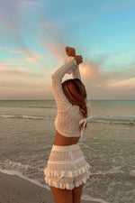 Side view of white knit ruffle shorts with three tiers of ruffles and a textured open-knit pattern