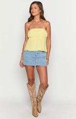 Front view of a yellow strapless top with a gathered elasticated bust and a flowy peplum hem