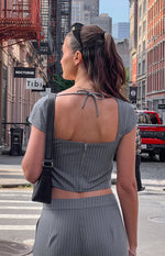Rear view of a grey pinstripe top with a square back, tie detail at the neck, short sleeves, and a back zipper
