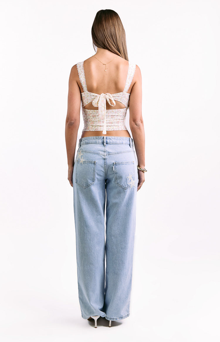 Rear view of a white floral corset top with a large tie-back bow, back cutouts, and lace-trimmed straps