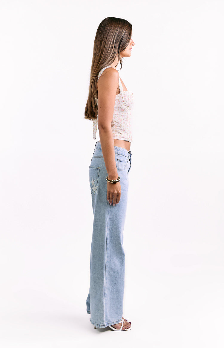 Side view of a white floral cropped corset top with thin straps and a tie-back