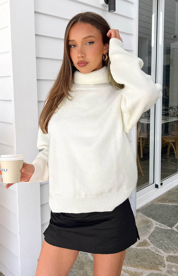 Cream knit turtleneck sweater with a relaxed fit, long sleeves, and ribbed cuffs