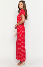 Side view of a red polka dot maxi dress with short puff sleeves and a flowing skirt