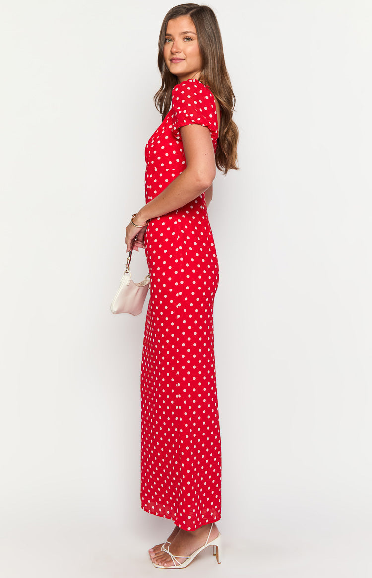 Side view of a red polka dot maxi dress with short puff sleeves and a flowing skirt