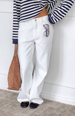 Close-up of the front of white denim slouchy jeans with a button fly and relaxed leg