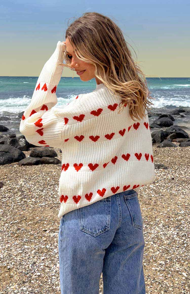 Textured cream knit jumper with rows of red heart patterns across the chest and sleeves