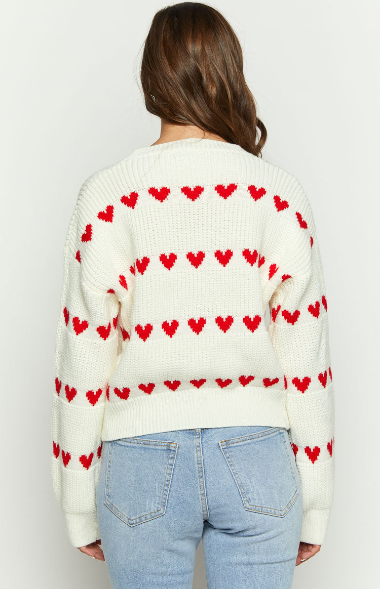 Rear view of a cream knit jumper with horizontal red heart stripes across the back and sleeves