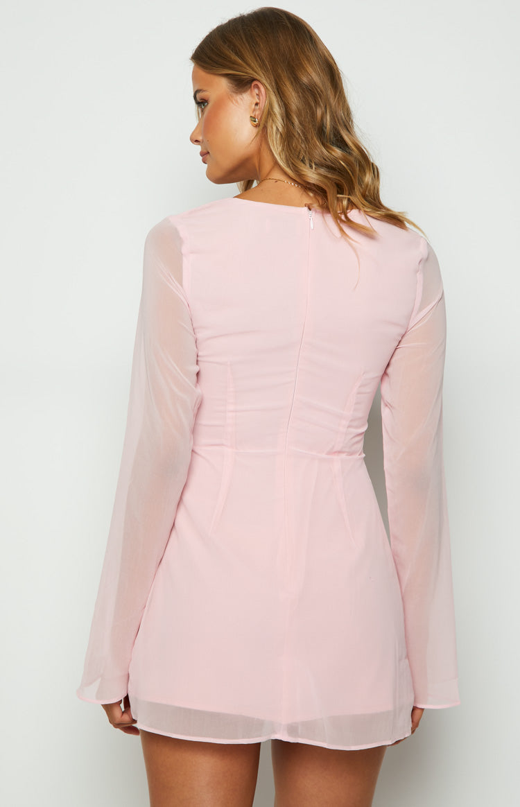 Rear view of a baby pink mini dress with a back zipper, ruched bodice, and sheer long sleeves