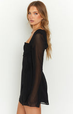 Side view of a black long sleeve mini dress featuring a square neckline, ruched bust, and side tie detail