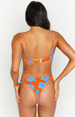 Rear view of orange floral bikini bottoms with blue and pink flowers, featuring a ruched thong cut