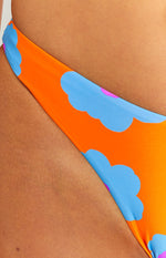 High-cut leg line of orange bikini bottoms with blue and pink cloud-like floral pattern