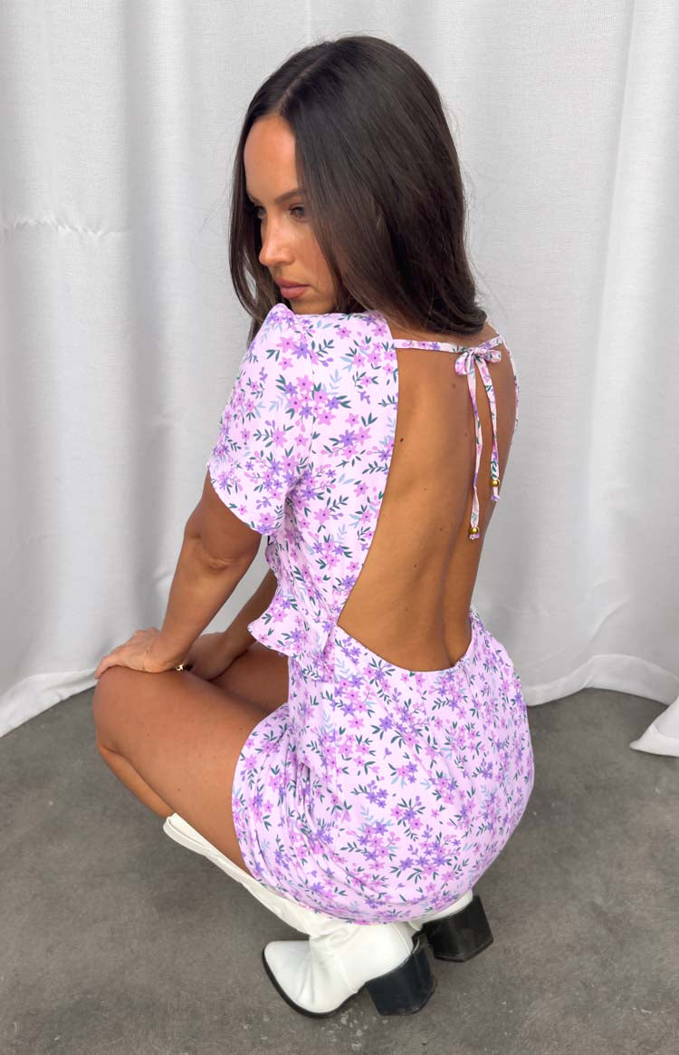Back view of a lilac floral mini dress with a large open back, a tie-back detail at the neck, and short sleeves