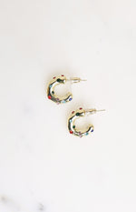 Flat lay of two gold mini hoop earrings with scattered red, green, blue, and pink stones and stud backs