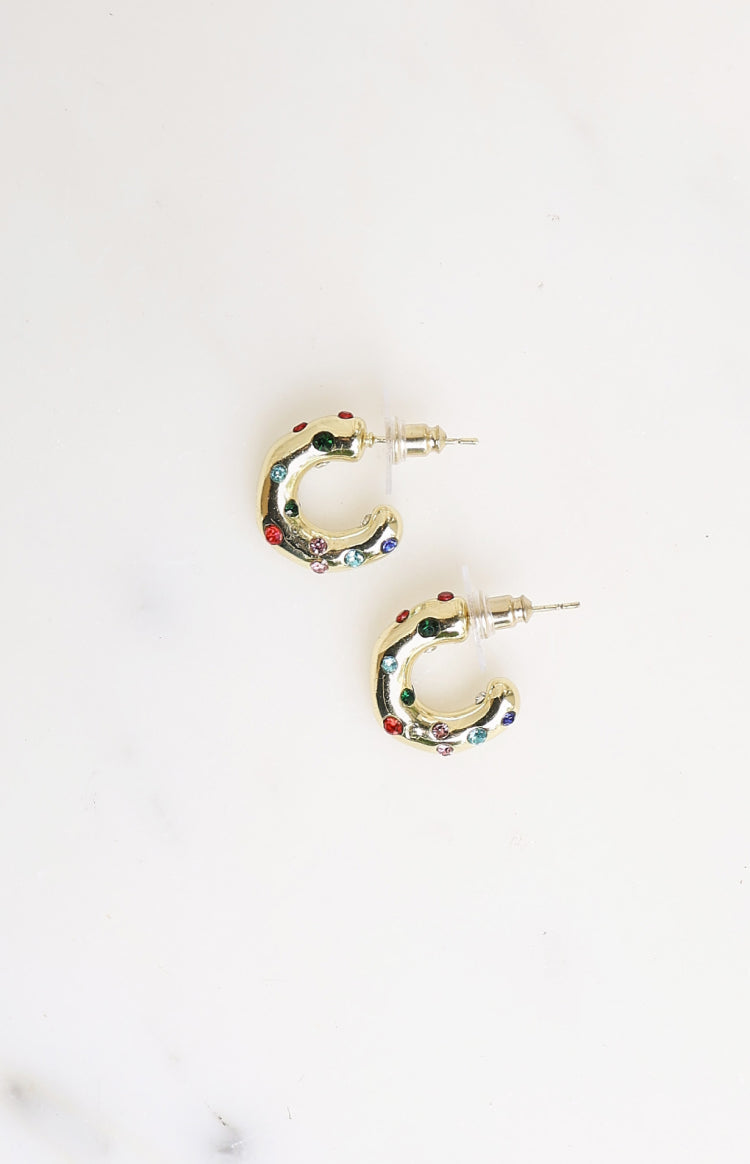 Flat lay of two gold mini hoop earrings with scattered red, green, blue, and pink stones and stud backs
