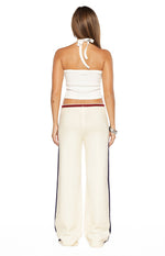 Rear view of cream knit jacquard track pants with a red and navy striped ribbed waistband and navy side stripes