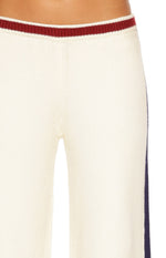 Close-up of the cream knit track pants with a red ribbed waistband and blue side stripe