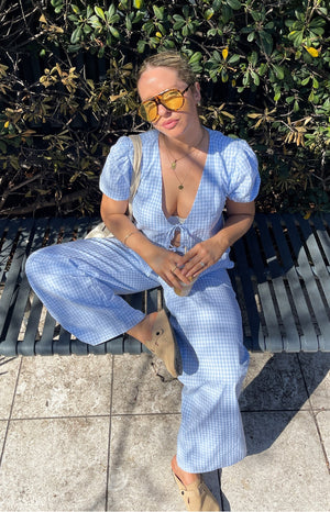 Close up of girl wearing blue gingham pants and a white tank top.