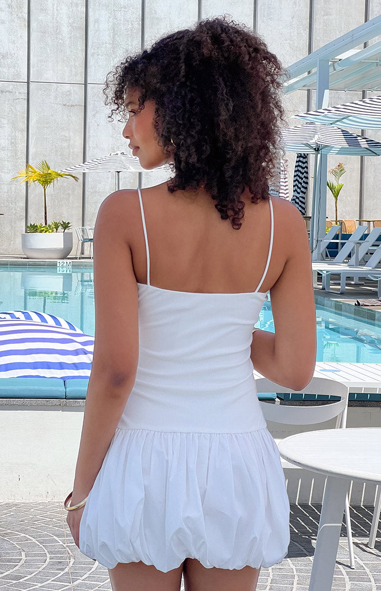 Back view of a white mini dress showing the straight neckline, thin spaghetti straps, and full bubble skirt