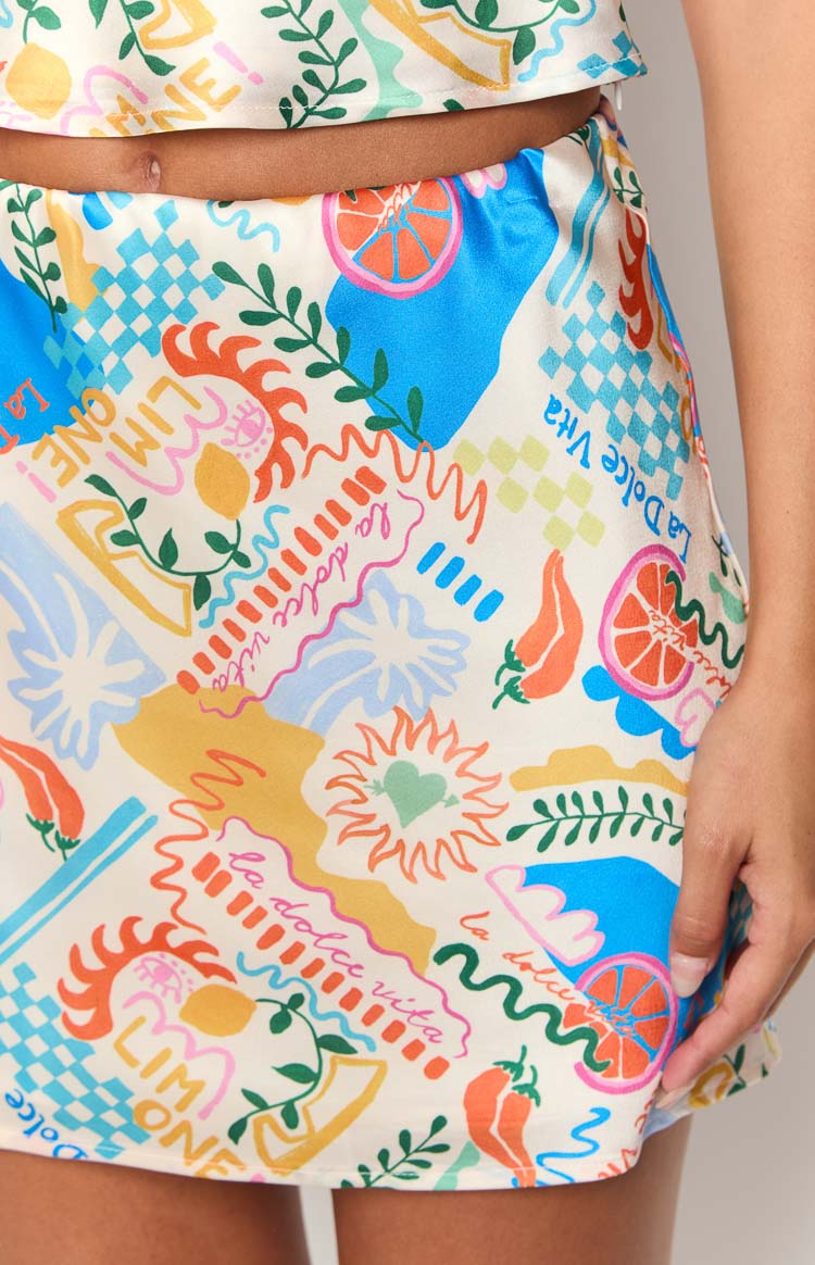 Close-up of the vibrant 'La Dolce Vita' print mini skirt featuring lemons, chili peppers, suns, and checkered patterns