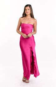 Front view of a hot pink satin strapless maxi dress with a ruffled high leg slit