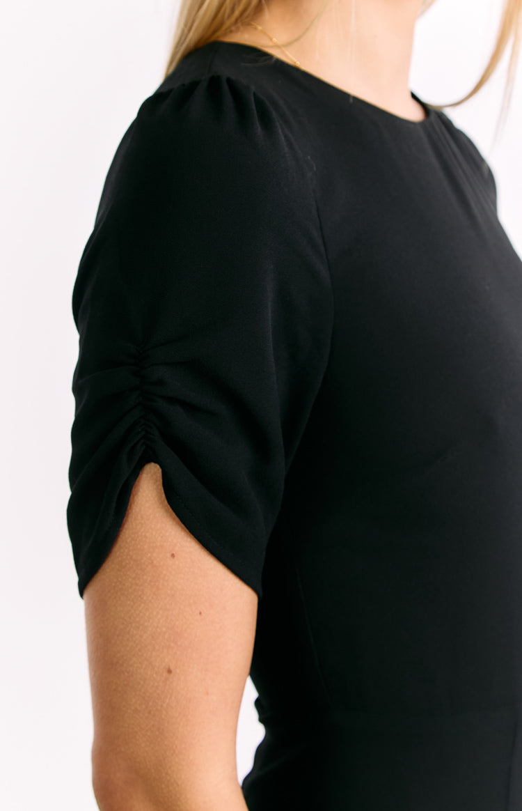 Ruched short sleeve with a slight puff at the shoulder of the black mini dress