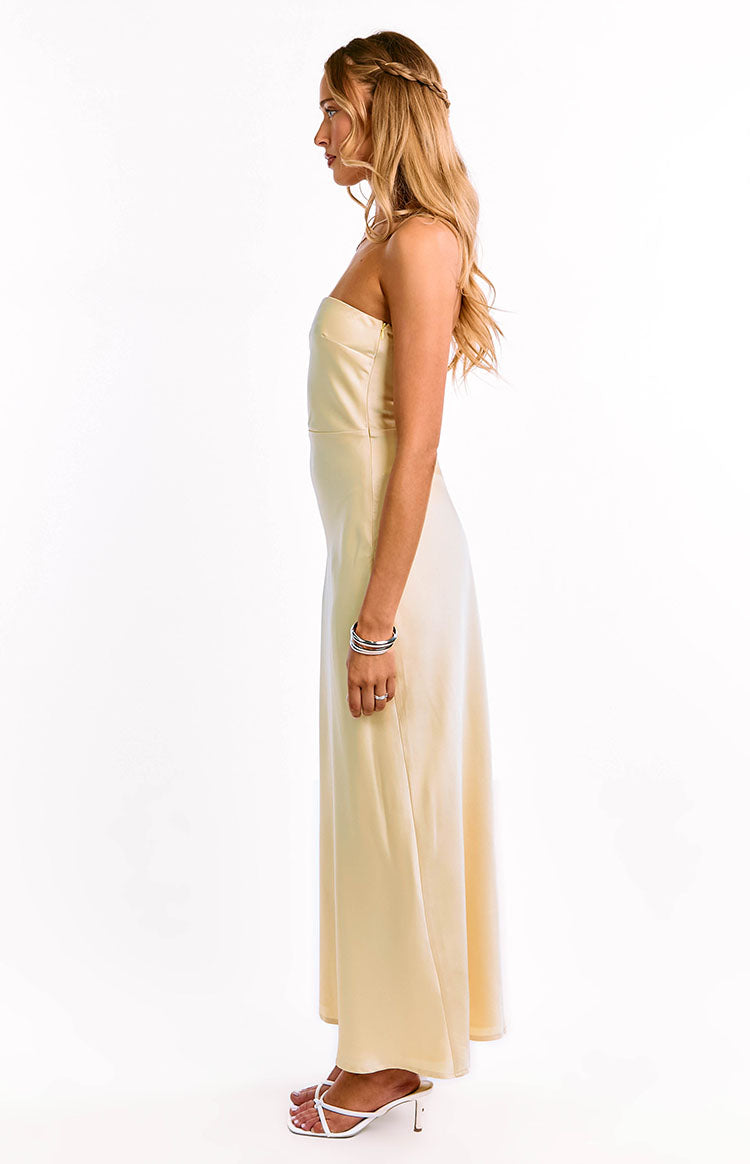 Side view of a pale yellow strapless maxi dress with a fitted bodice and flowy skirt