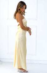 Side view of a yellow satin strapless maxi dress with a bandeau neckline and side waist cutout detail