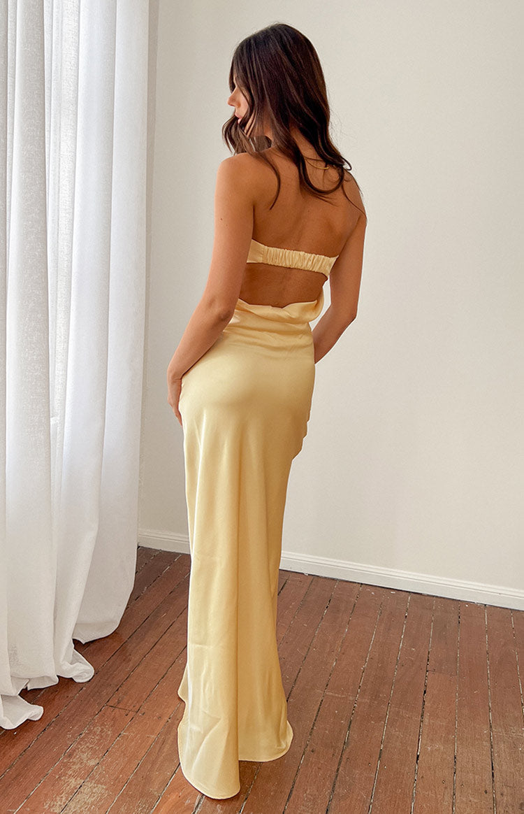 Pale yellow strapless maxi dress with a fitted bodice, subtle horizontal seams, and a flowing skirt