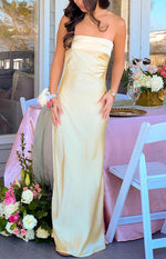 Full length view of a yellow strapless maxi dress with a folded band neckline and a flowy satin skirt