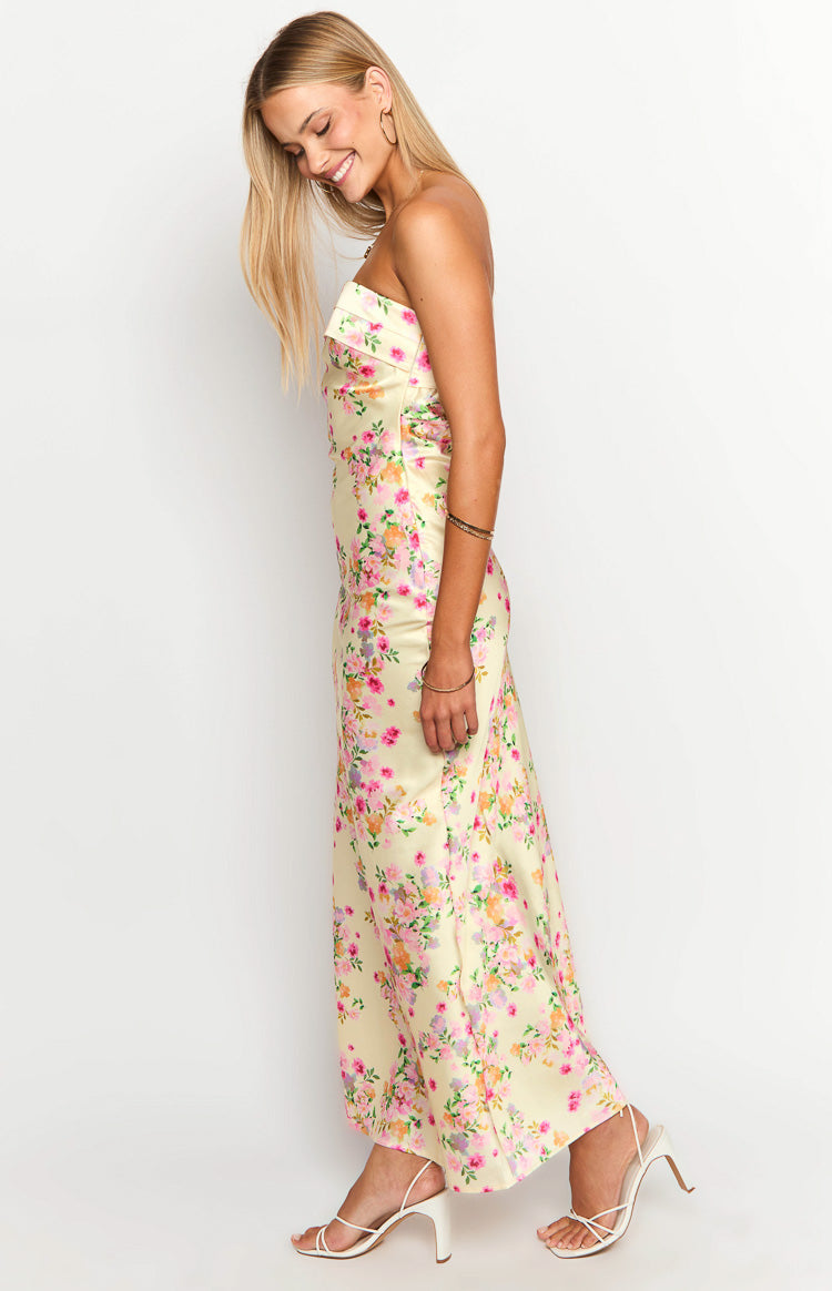 Side view of a yellow floral strapless maxi dress with a fitted bodice and flowy skirt