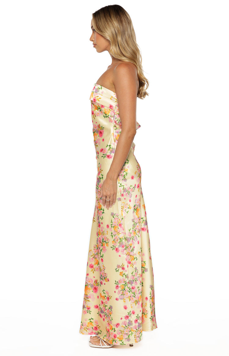 Side view of a yellow floral strapless maxi dress with a fitted bodice and flowing skirt