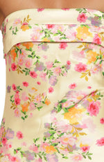 Close-up of the banded strapless neckline and yellow satin floral print of a maxi dress