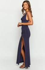Side view of a navy maxi dress with a cowl neck, spaghetti straps, side ruching, and a high leg slit