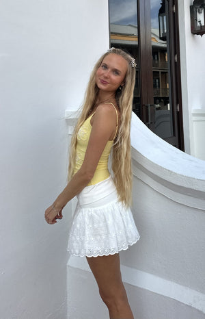 Side view of a yellow beaded top with floral embroidery and thin spaghetti straps