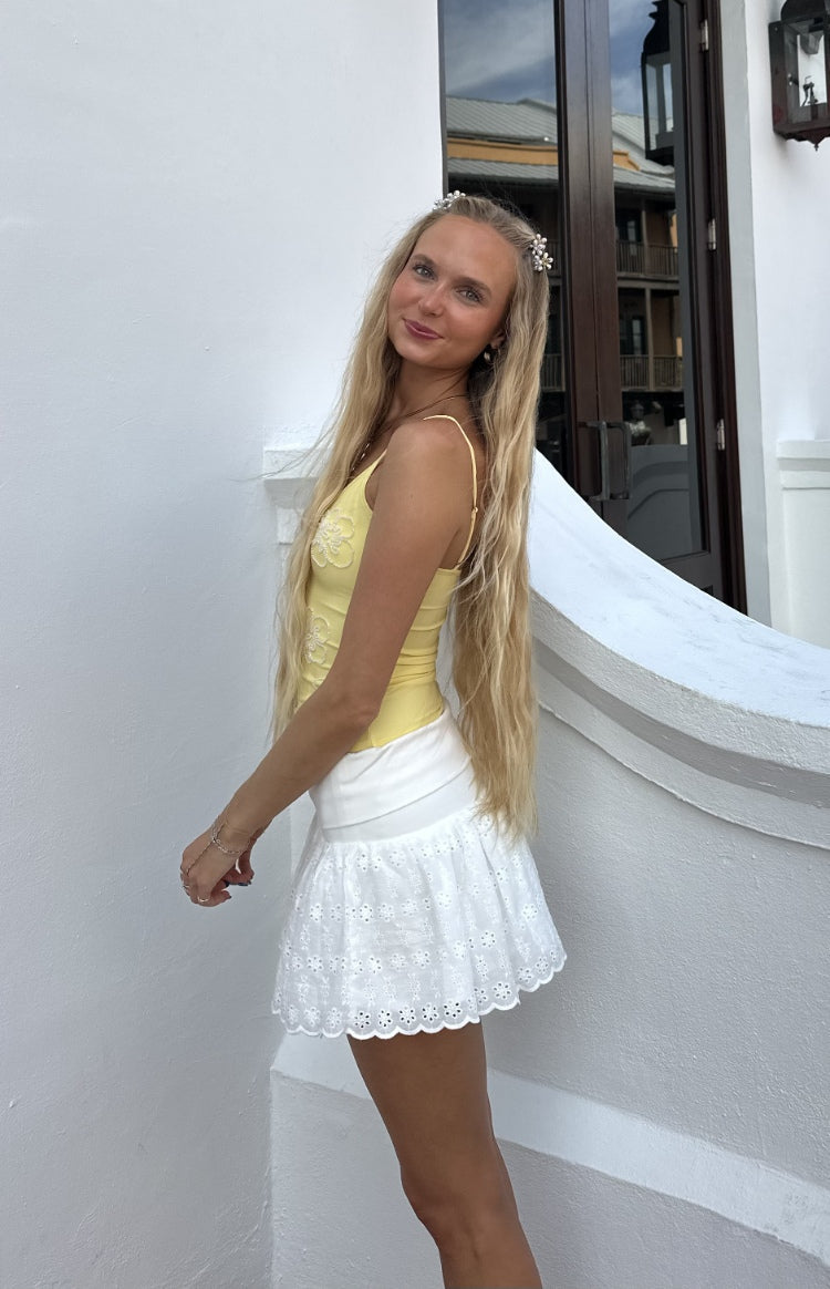 Side view of a yellow beaded top with floral embroidery and thin spaghetti straps