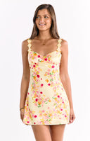A charming yellow satin mini dress with a sweet pink and orange floral print- featuring a flattering sweetheart neckline and delicate spaghetti straps adorned with small floral embellishments- suitable for a spring party.