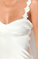 Close-up of the white satin mini dress showing the floral applique shoulder strap and side zipper