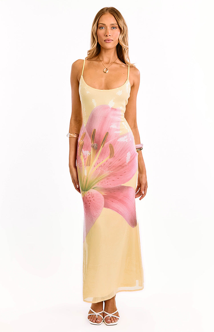 Front view of a yellow sequin maxi dress with a scoop neckline, delicate spaghetti straps, and a large pink lily print