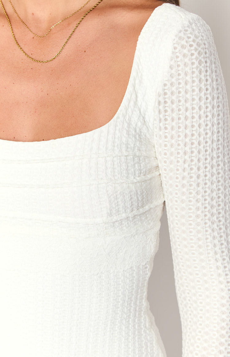 Close-up of the white square neck mini dress with horizontal ruching on the bodice and sheer dotted long sleeve