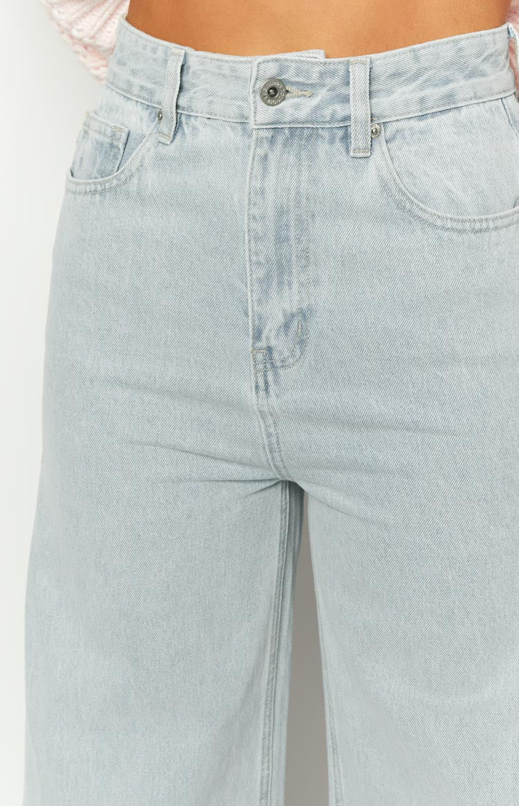 Close-up of the light wash denim jeans showing the high waist, front button, and curved front pockets