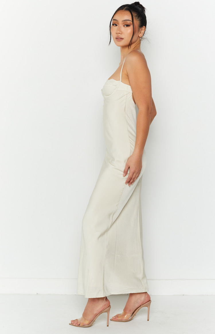 Side view of a cream midi dress with spaghetti straps and a fitted bodice flowing to a relaxed skirt