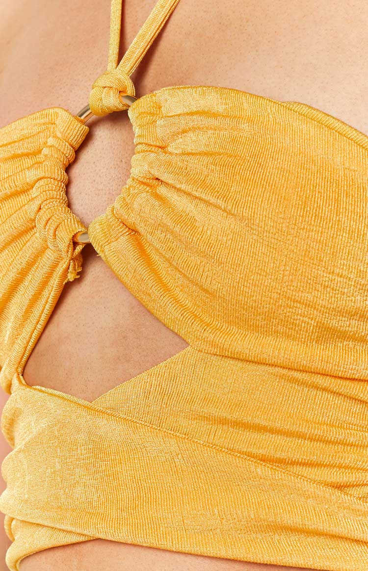 Close-up of the gold ring and ruched detail on the yellow halter top, highlighting the side cut-out