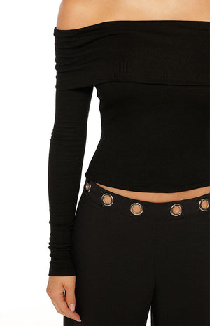 Woman wearing a black ribbed off-shoulder long sleeve top with dark trousers a versatile staple for a Fall wardrobe